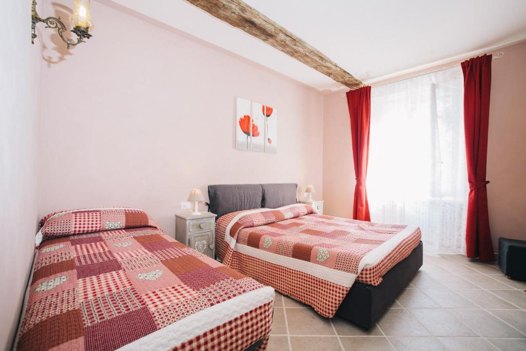 ヴェナリア・レアーレにあるLe Dimore di Dianaの赤いカーテンが備わるドミトリールームのベッド2台分です。