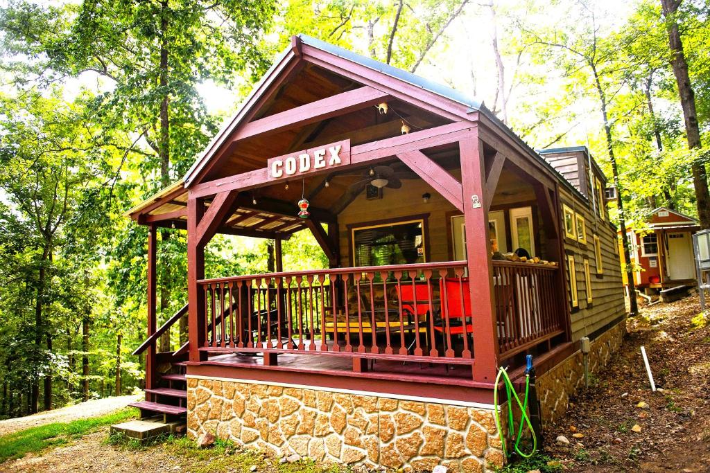 a small cabin with a porch in the woods at The Codex - Parker Creek Bend Cabins in Murfreesboro