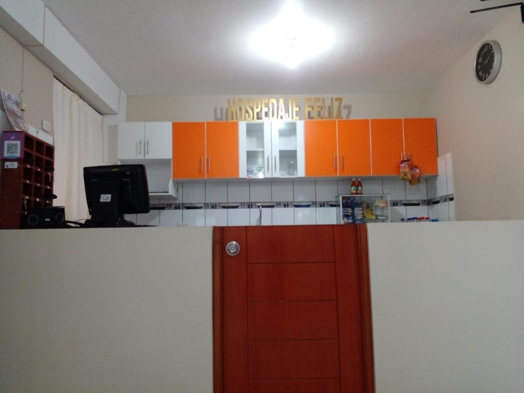 een keuken met oranje kasten en een rode deur bij Hospedaje Feliz in Chimbote
