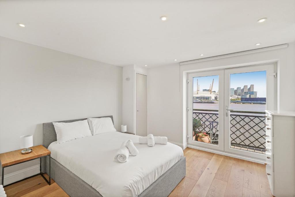 a white bedroom with a bed and a window at Monthly Stays! 2 Bed Stunning Riverside Apartment in London