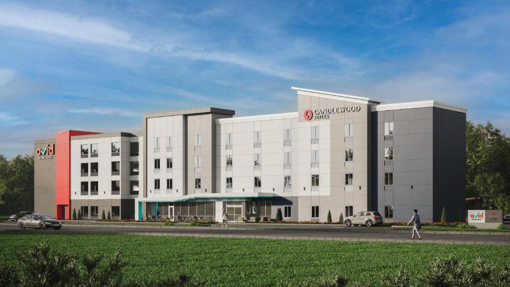 un grand bâtiment blanc avec une personne qui marche devant lui dans l'établissement Candlewood Suites Fort Payne, an IHG Hotel, à Fort Payne