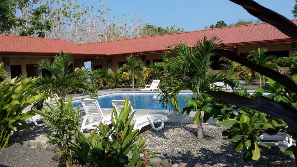 a resort with a swimming pool with chairs and palm trees at Hotel D'Lucia - Quebrada Ganado, Jaco, Costa Rica in Puntarenas