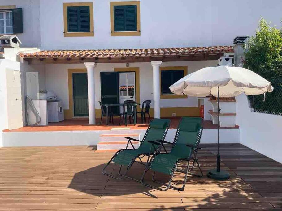 une terrasse avec des chaises et un parasol en face d'une maison dans l'établissement Casa do Almograve, à Odemira