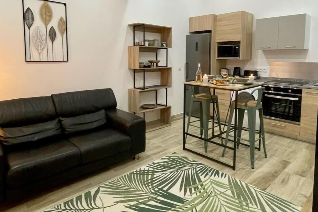 a living room with a black couch and a kitchen at Perpignan Centre : Superbe appartement en Roof-top in Perpignan