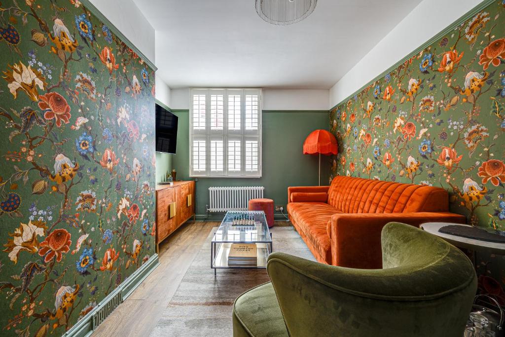 sala de estar con sofá naranja y papel pintado con motivos florales en Insta-worthy Loft on Historic Chester Rows, Sleeps 4 & Free Parking en Chester