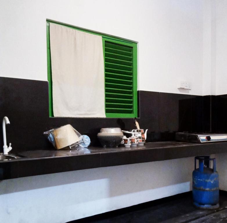 a kitchen with a black counter with a green window at Green Bird in Mirissa