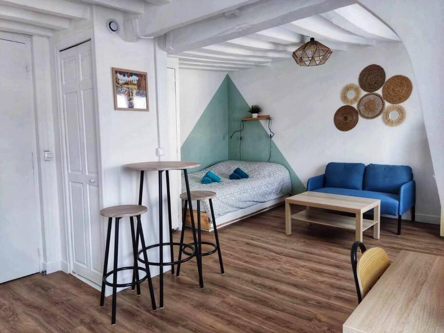 ein Wohnzimmer mit einem blauen Sofa und 2 Barhockern in der Unterkunft Au p'tit Lagny - rue piétonne in Lagny