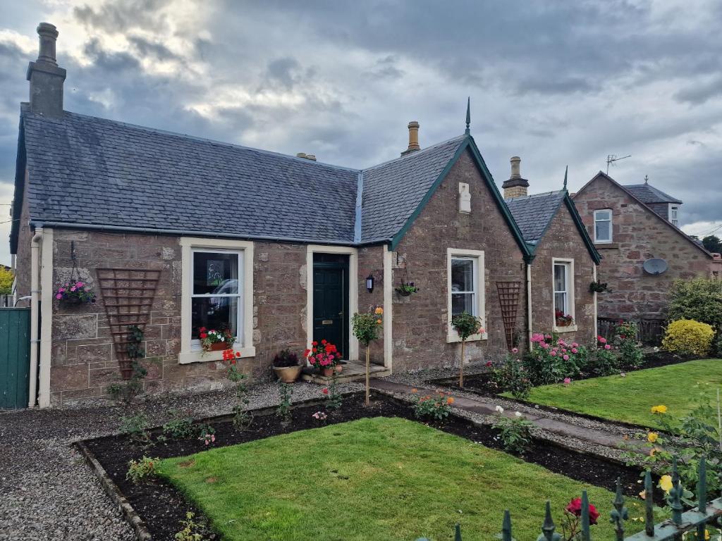 a brick house with a garden in front of it at Isla Rose Cottage in Blairgowrie