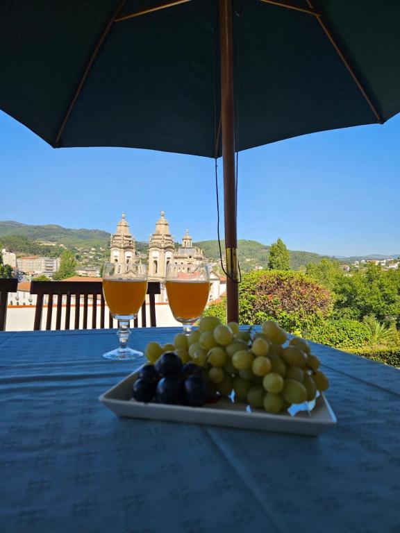un piatto di frutta su un tavolo con due bicchieri di vino di Casa das Acácias a Cabeceiras de Basto