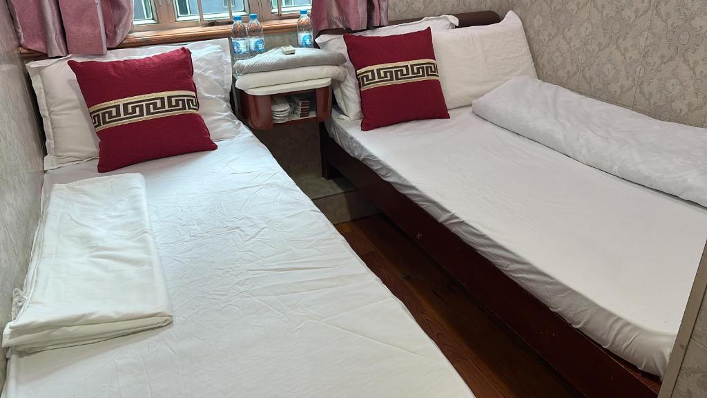 two beds in a room with red and white pillows at Piaget guest house in Hong Kong