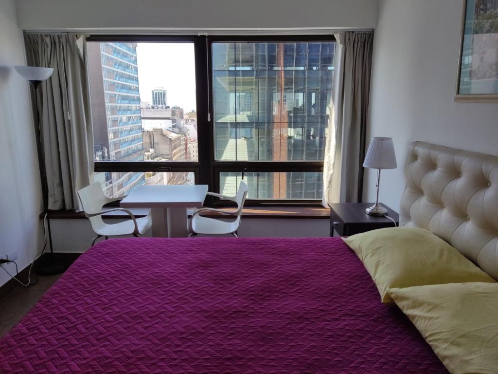 een slaapkamer met een groot bed met een groot raam bij Buenos Aires Center Apart in Buenos Aires