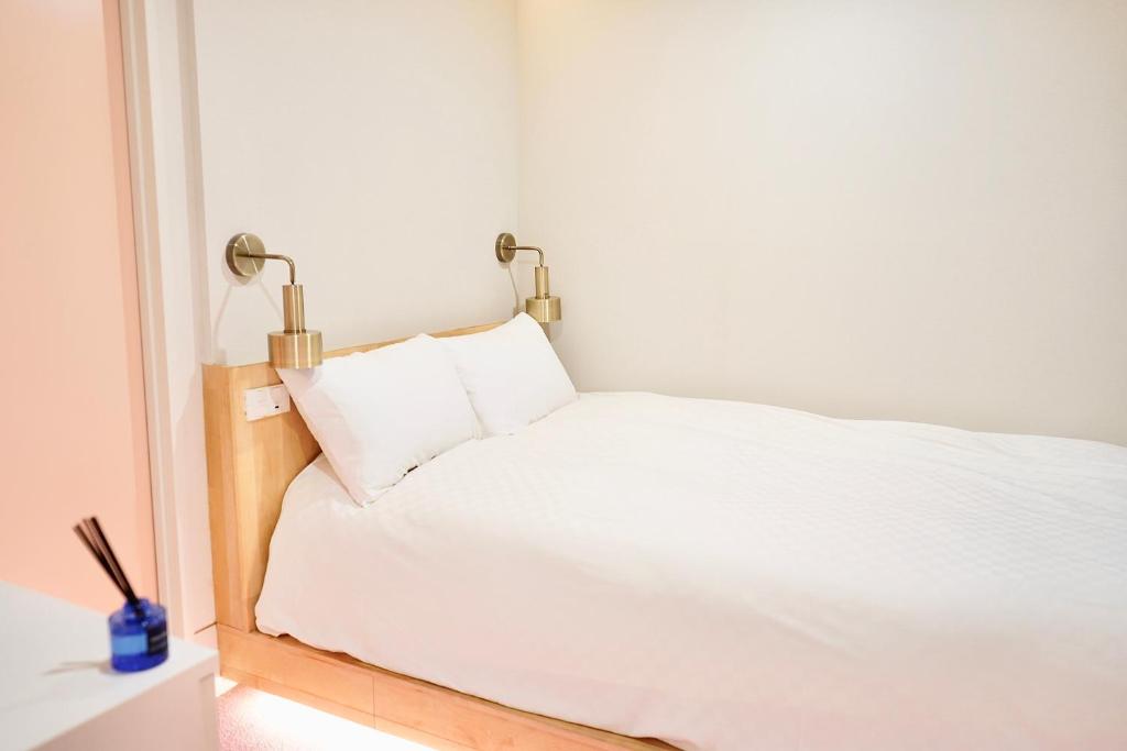 a white bed with two lamps on top of it at 东京上野超级中心 设计师房间Yaoa 上野公园3分钟 车站1分钟 超级繁华 免费wifi 戴森吹风 in Tokyo