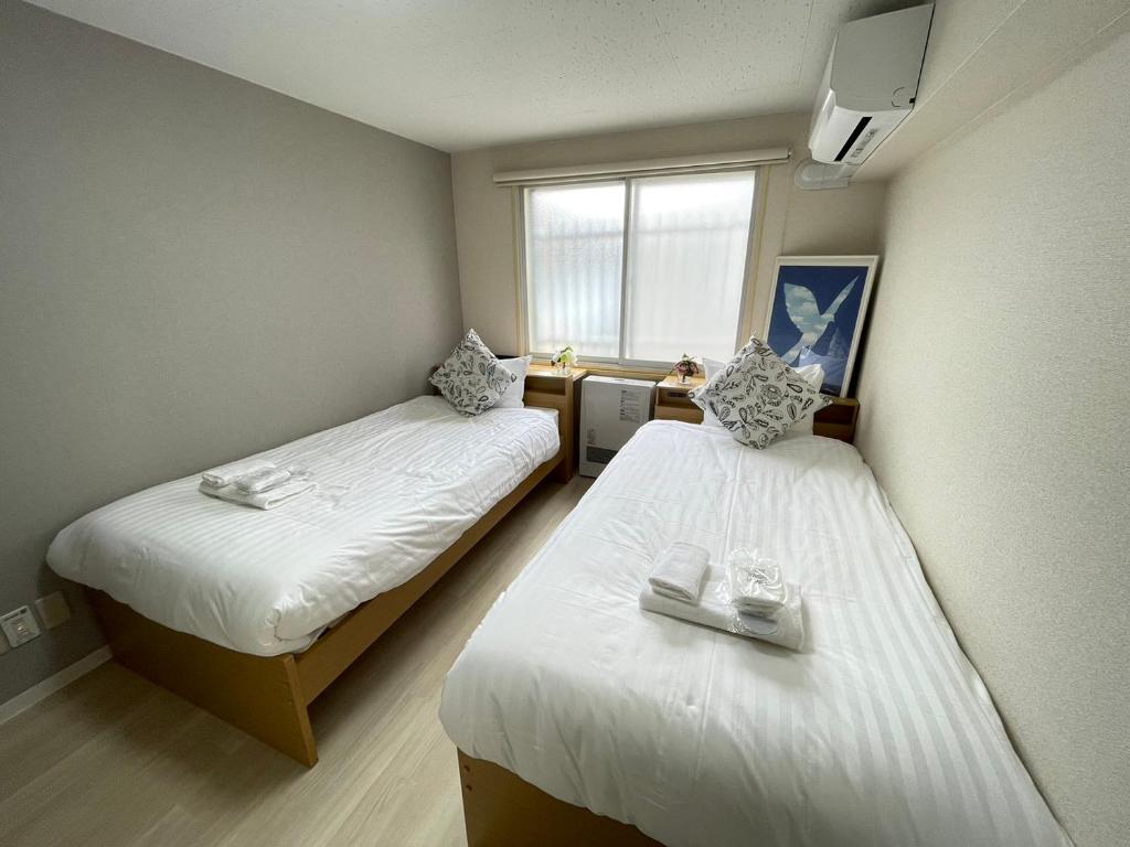 two beds in a small room with a window at NORTH LIVE 2 in Ōdōri
