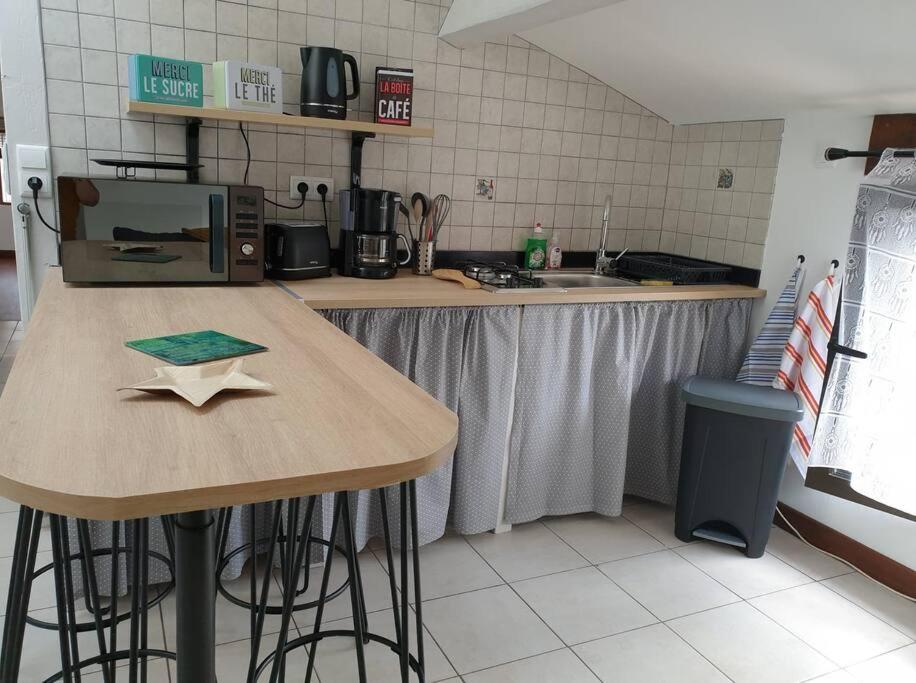 a kitchen with a counter and a table with stools at l'escapade in Gasny