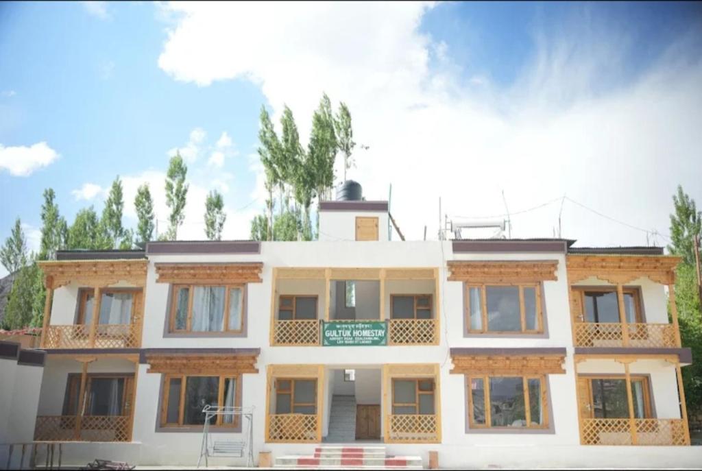 a large white building with trees in the background at gultuk home stay in Leh