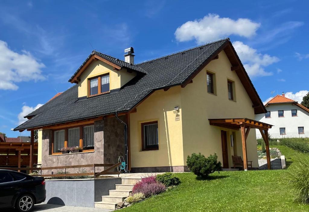 a yellow house with a black roof at Apartmán u Kovářů in Kašperské Hory