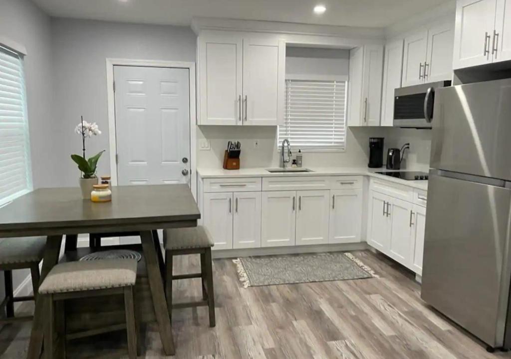 a kitchen with white cabinets and a table and a refrigerator at Downtown West Palm Apartment Near Airport in West Palm Beach