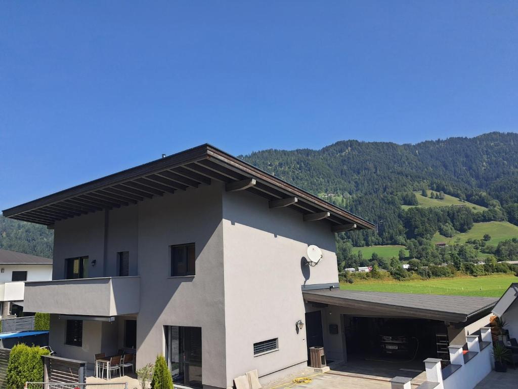 a white building with a mountain in the background at Glück auf - Ferienhaus zum Rauchfangkehrer in Wörgl