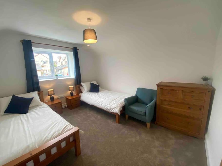 - une chambre avec deux lits et une chaise bleue dans l'établissement High Tide Cottage, à Swansea