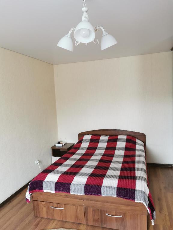 a bedroom with a bed with a plaid blanket on it at 1 комн апартаменты в центре рядом с парком in Kostanay