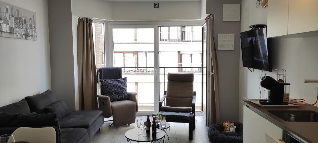 a living room with a couch and chairs and a window at Les Courlis 0203 in De Panne