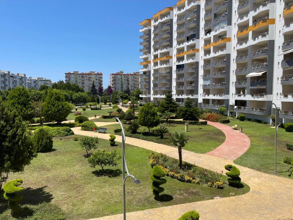 a large apartment building with a park in front of it at Queenaba tatil sitesi in Mersin