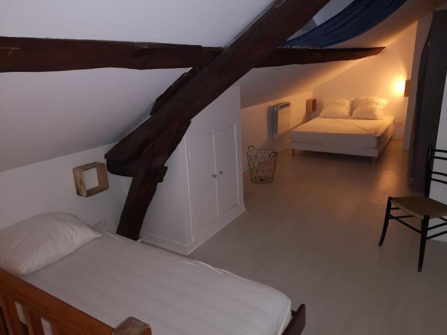 a attic bedroom with a bed and a chair at Hypercentre résidence paisible in Fontainebleau
