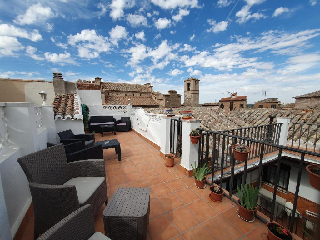 uma varanda com cadeiras e mesas num telhado em ToledoRooms Estrella - M, L, XL, XXL - Pisos con Azotea - Sun Terrace em Toledo