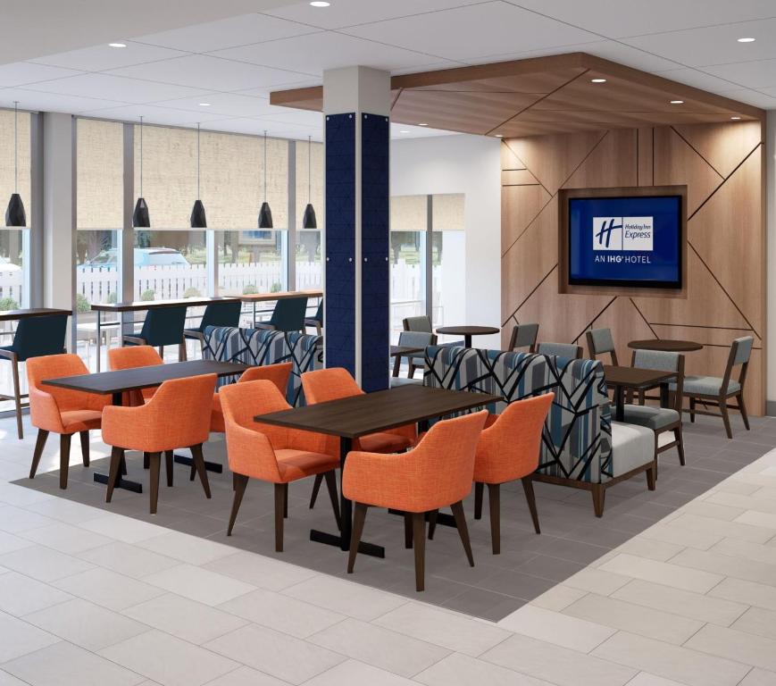 a restaurant with tables and chairs and a tv at Holiday Inn Express & Suites Ormond Beach - North Daytona, an IHG Hotel in Ormond Beach