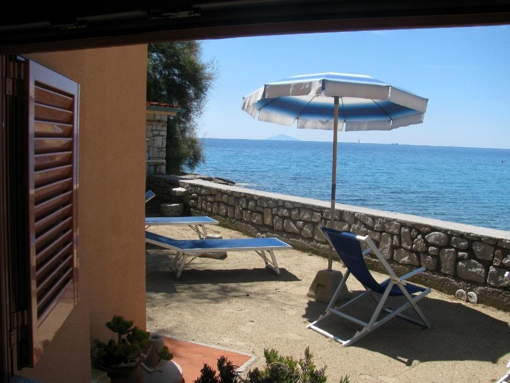 two chairs and an umbrella next to the ocean at Onda Su Onda Appartamenti in Seccheto
