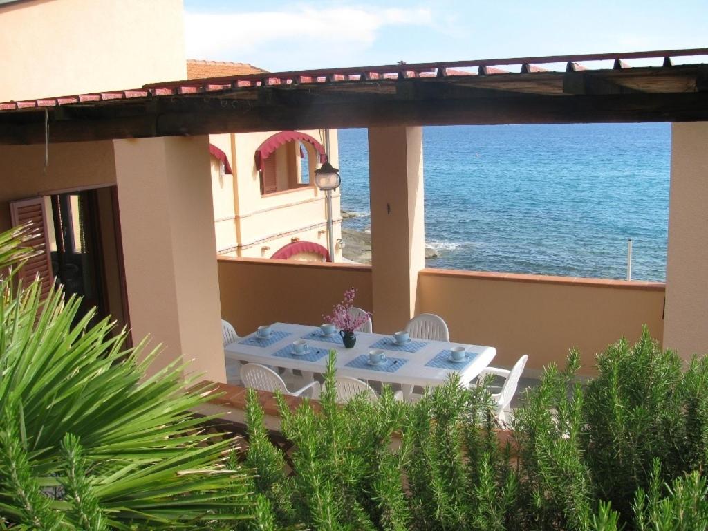 a table on the balcony of a house with the ocean at Onda Su Onda Appartamenti in Seccheto