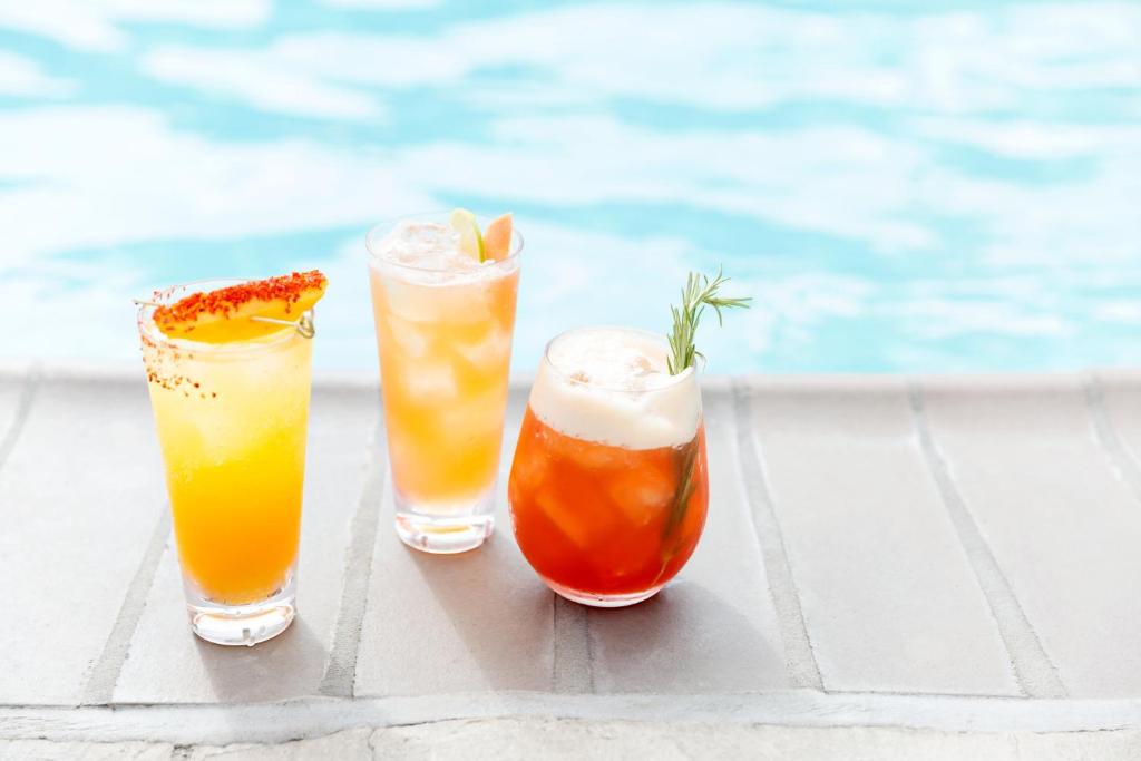 três cocktails sentados numa mesa ao lado de uma piscina em Kimpton Virgilio em Cidade do México