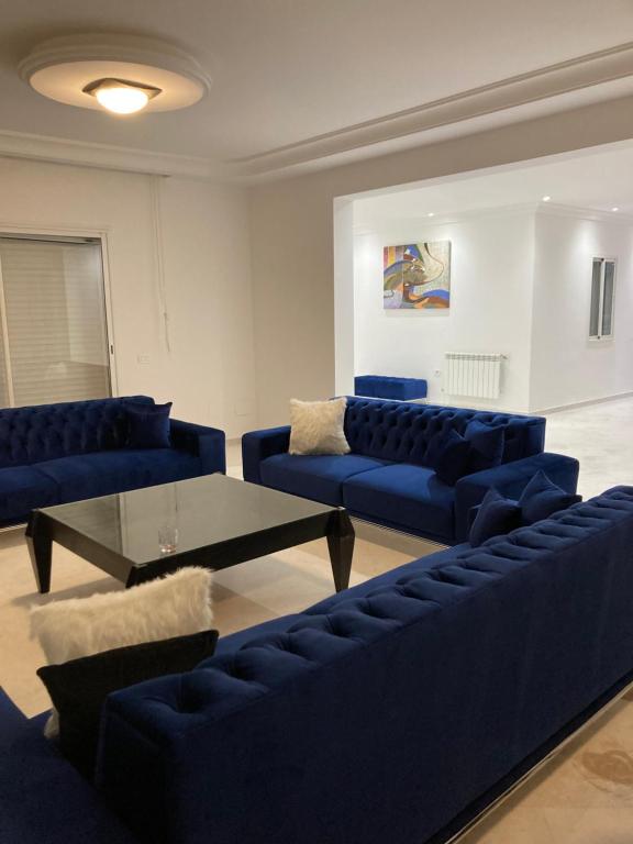 una sala de estar con sofás azules y una mesa. en Appartement haut standing 170 m2, en Túnez