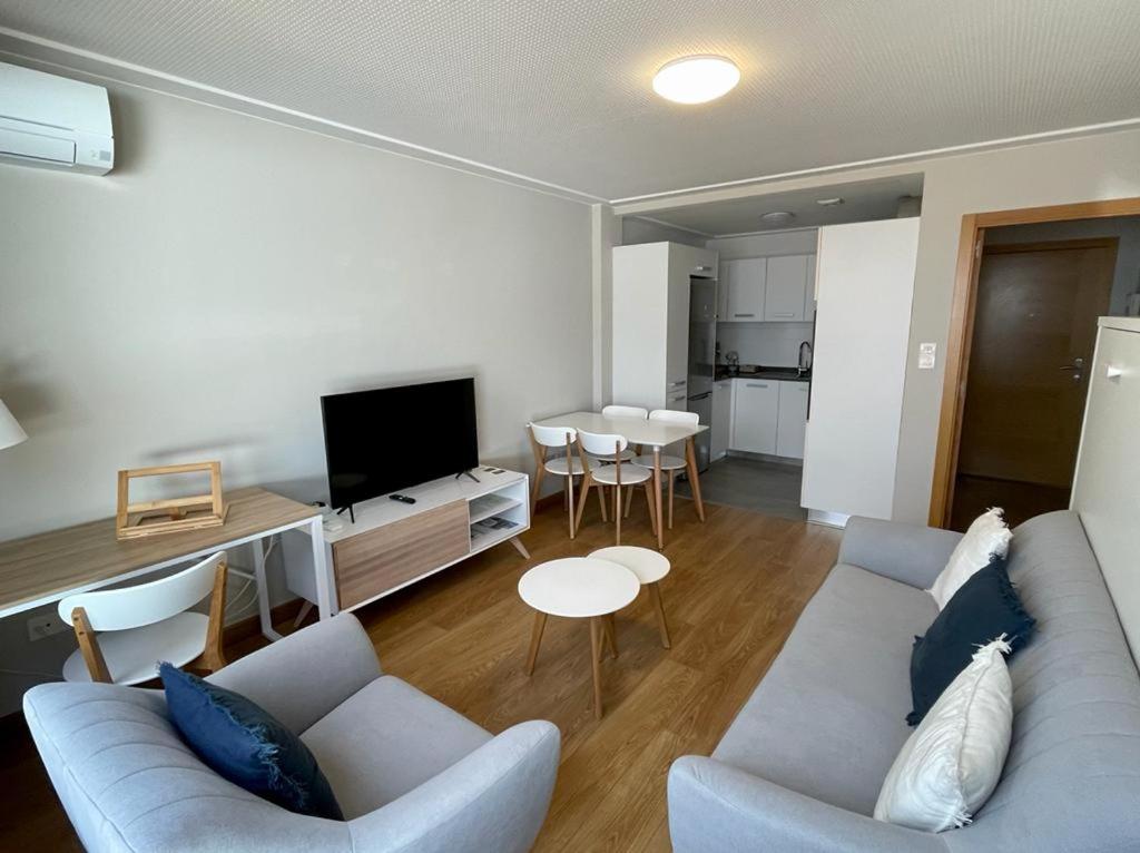 sala de estar con sofá azul y cocina en Estudio céntrico 2 con terraza y parking privado, en Ourense
