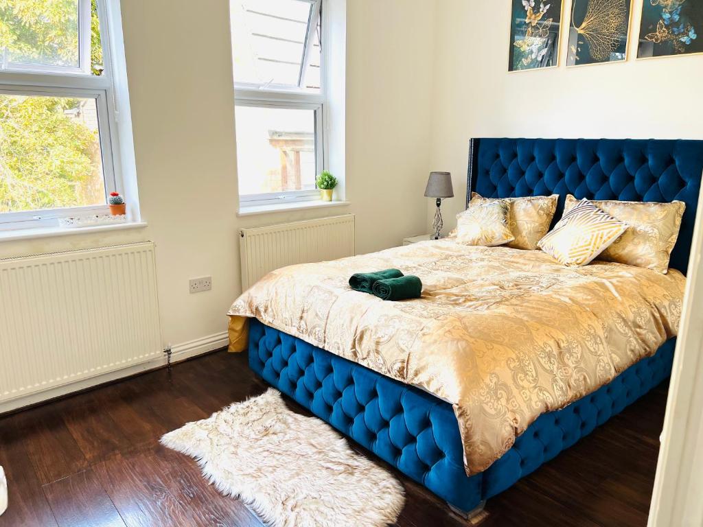 a blue bed in a bedroom with two windows at Luxury Morden 4 bedroom Flats which will make you unforgettable in London