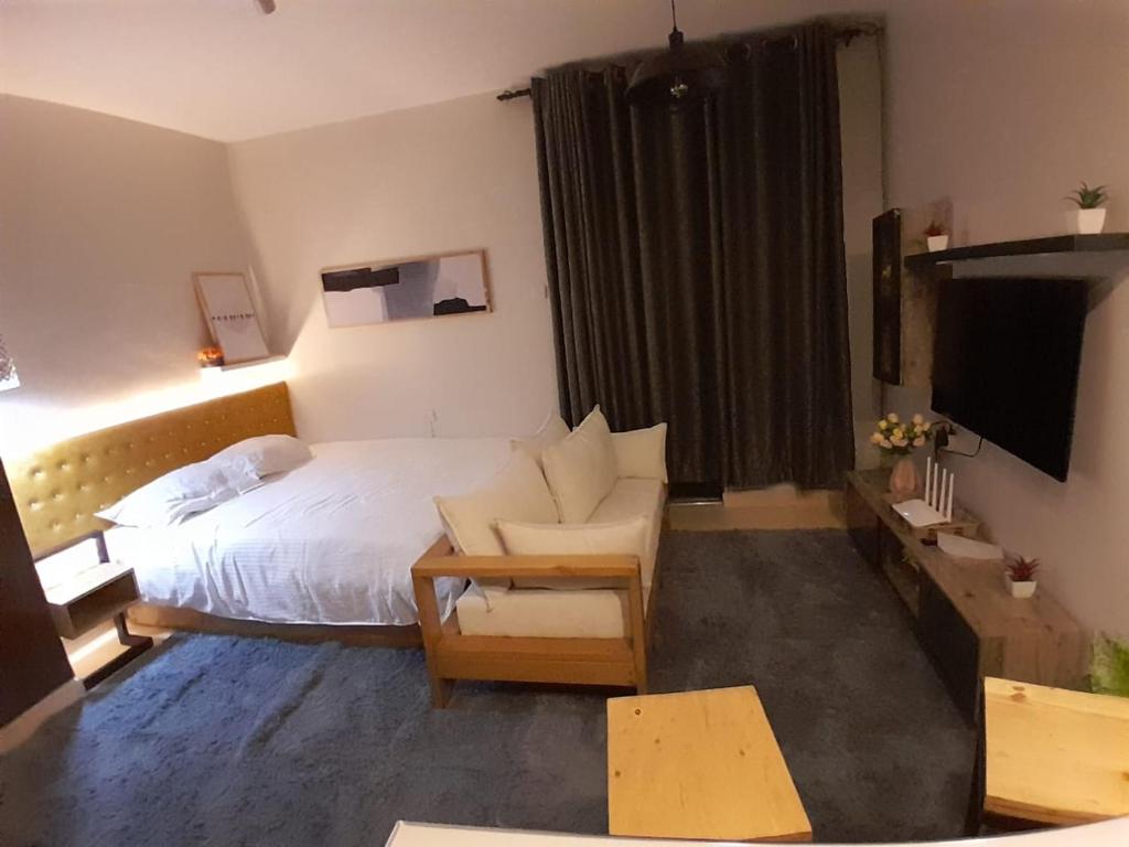 Bungoma的住宿－EnN Lovely En suite studio apartment，酒店客房配有床、沙发和电视。