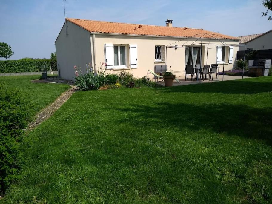 une petite maison blanche avec une cour gazonnée dans l'établissement Charmante maison, à Sainte-Blandine