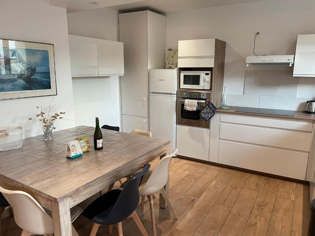 - une cuisine avec une table en bois, des chaises et une bouteille de vin dans l'établissement Maison rénovée au calme, à Biéville-Beuville
