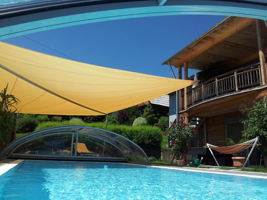 un grand parasol jaune au-dessus de la piscine dans l'établissement Villa Bellavista, à Labientschach