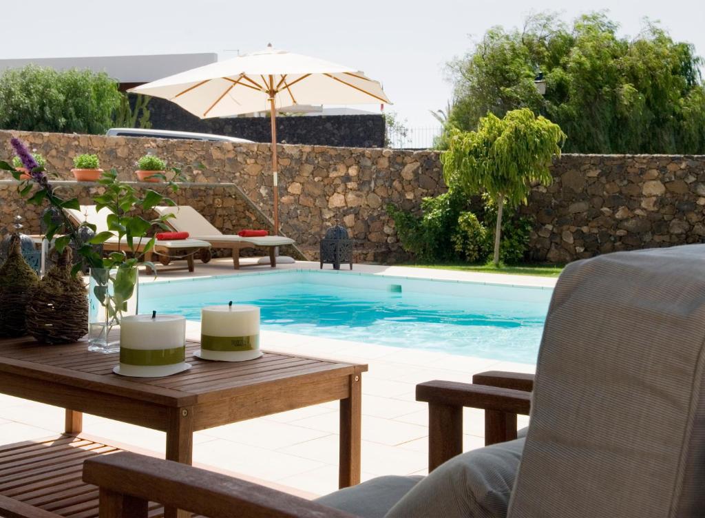 uma piscina com uma mesa e cadeiras e um guarda-sol em Villa Coral em Puerto del Carmen