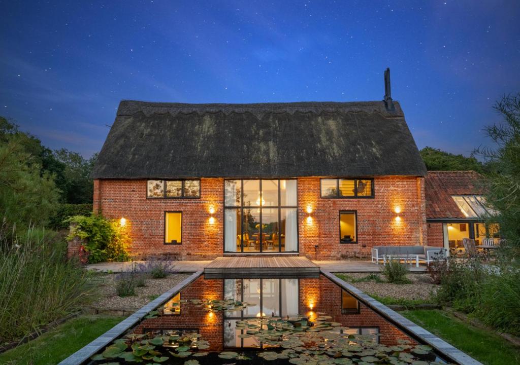 a brick house with a pond in front of it at Alexandra Barn in Shadingfield