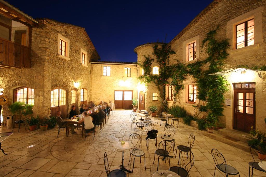 a group of people sitting at tables in a courtyard at Auberge La Plaine in Chabrillan
