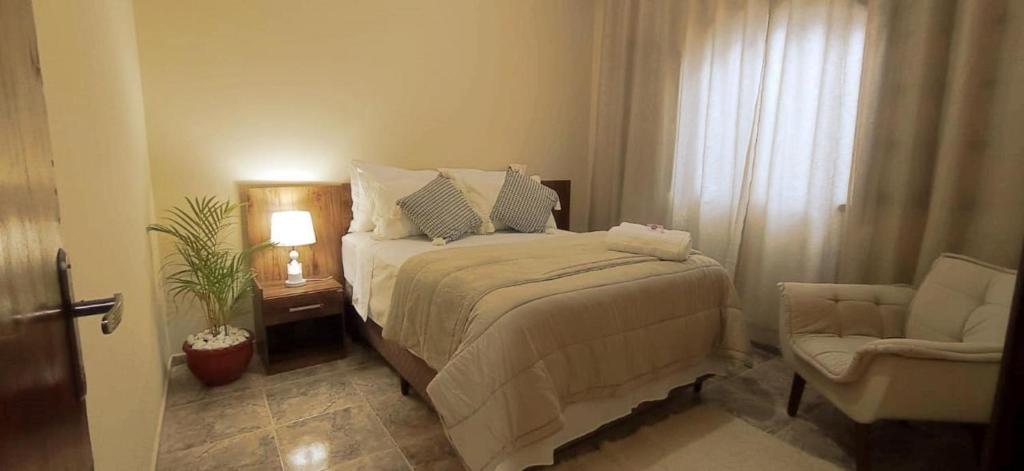 1 dormitorio con 1 cama, 1 silla y 1 ventana en Recanto das Neves, en Miguel Pereira