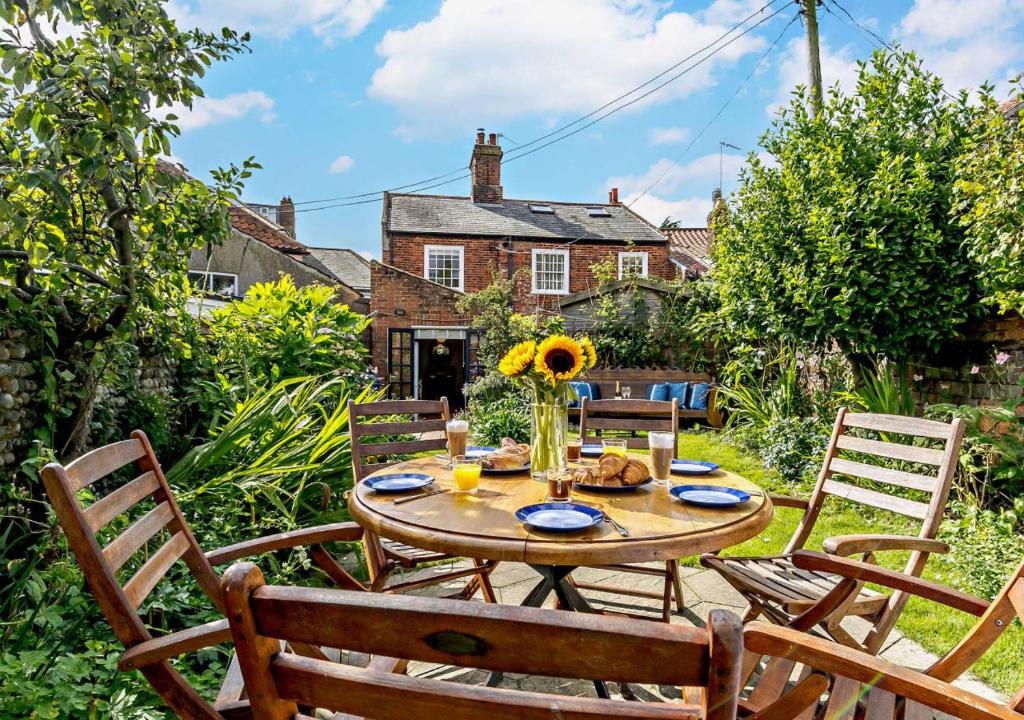 a patio with a table and chairs in a garden at Celebration Cottage - Southwold in Southwold