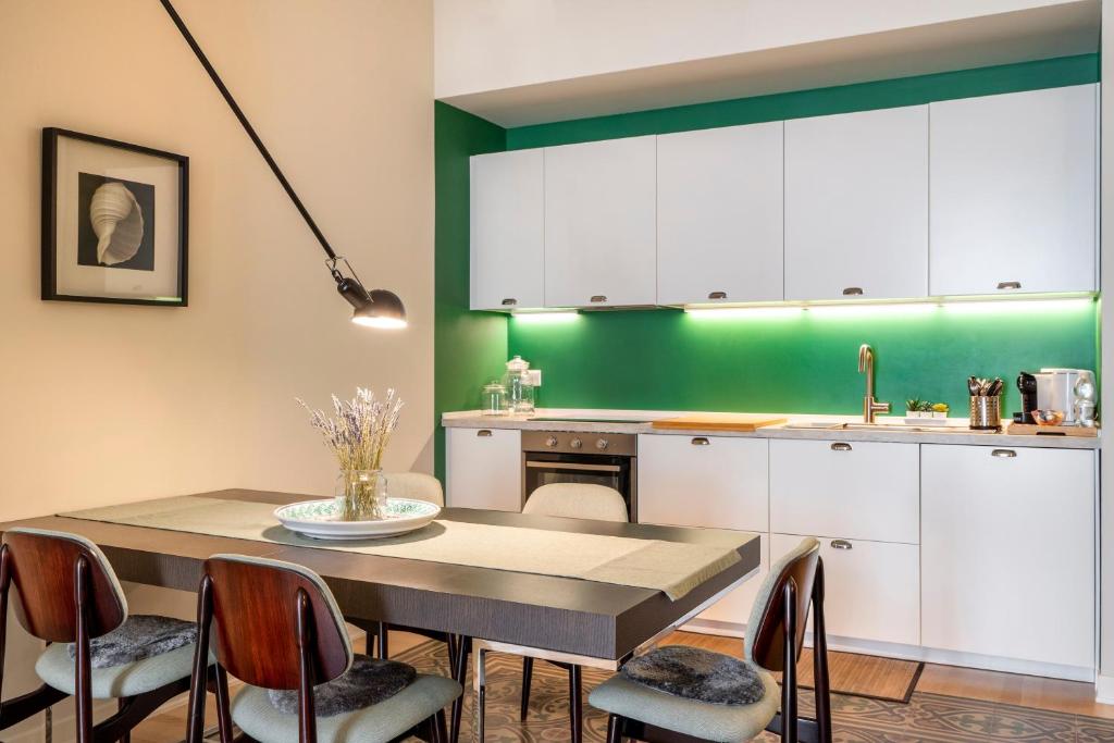 a kitchen with a table and chairs and a green wall at Luxury stay experience in Bari in Bari
