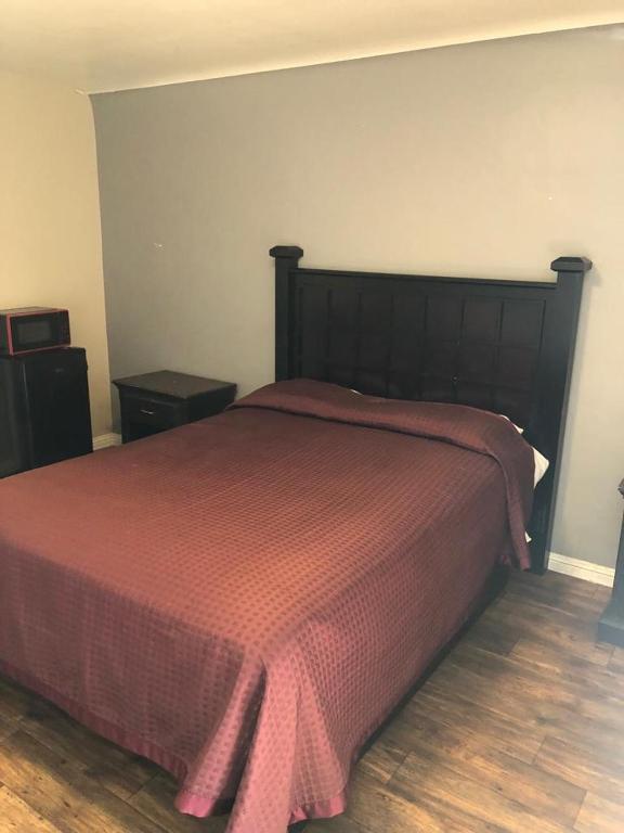 a bedroom with a large bed with a red blanket at Star Motel in Norwalk