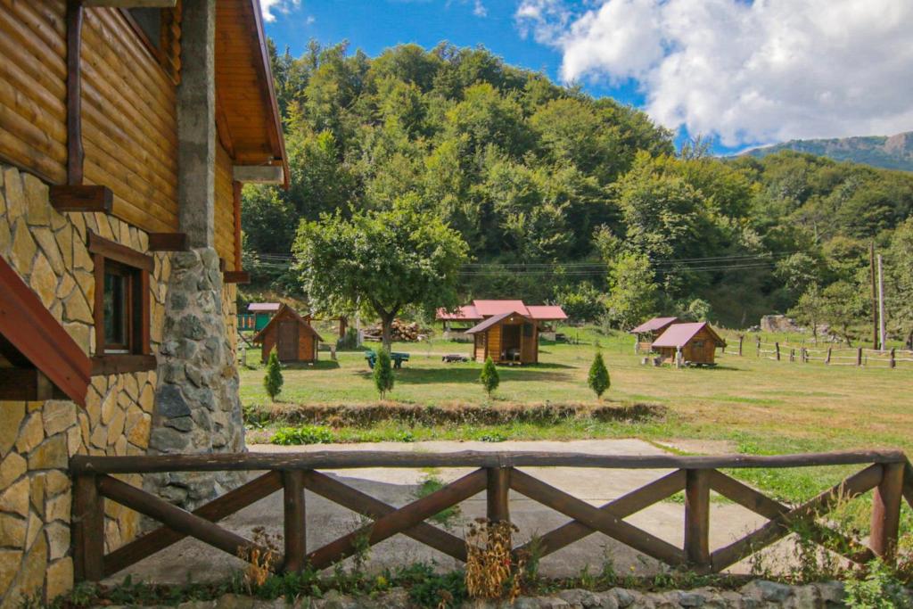 ein Gebäude mit einem Zaun neben einem Feld mit Häusern in der Unterkunft Camp &Apartmens Scepanovic in Mojkovac