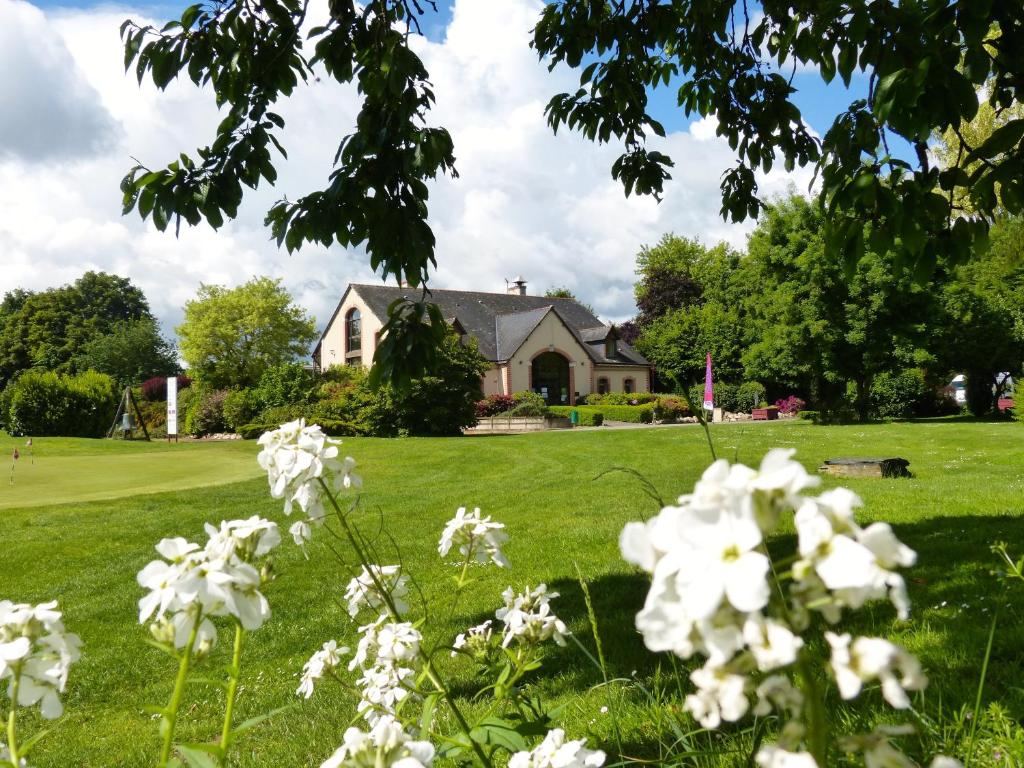 a house in a green field with white flowers at Anjou Golf and Country Club in Champigné