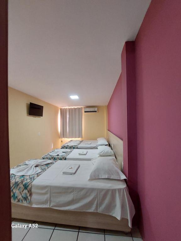 duas camas num quarto com uma parede rosa em Executivo Prime Hotel em Teresina