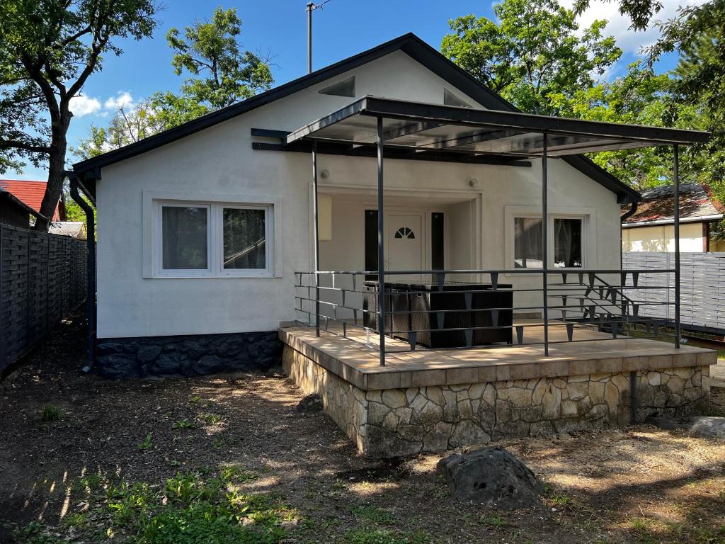 a small white house with a porch and a fence at TM House Sástó in Mátrafüred